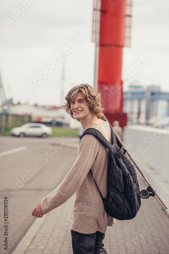 Hipster man dressed shirt, holding skateboard on shoulder, outdoor street portrait photo