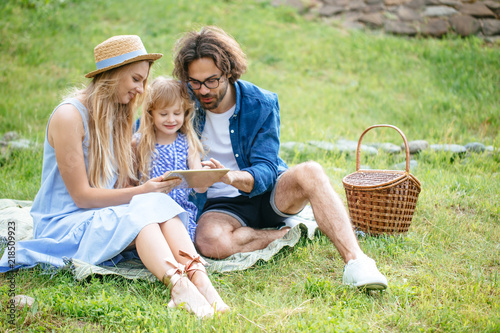 caucasian family using digital tablet during picnic at countryside photo