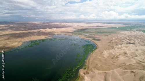 Panoramic view from above on a sandy desert with lakes. Flight over the barkhans in the desert. photo