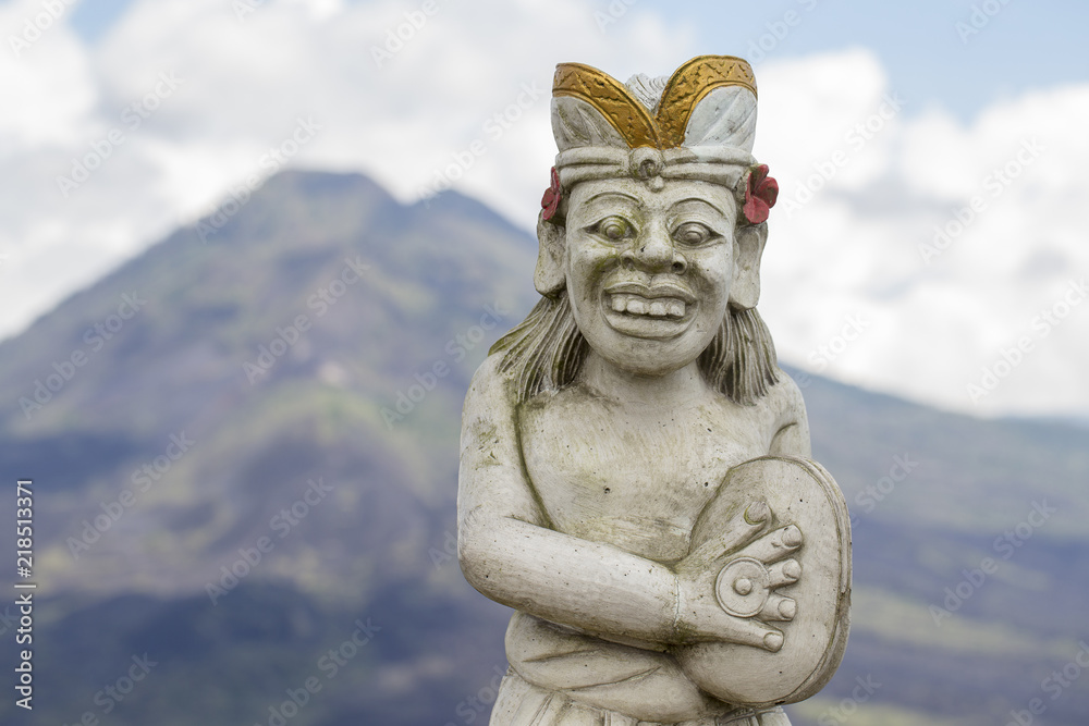 Traditional Balinese sculpture against the background of the volcano Batur. Island Bali, Indonesia. Closeup Traditional Balinese sculpture against the background of the volcano Batur. Island Bali, Indonesia. Closeup