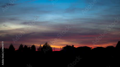 Silhouette of houses in village on beautiful red sunset © Stasyuk