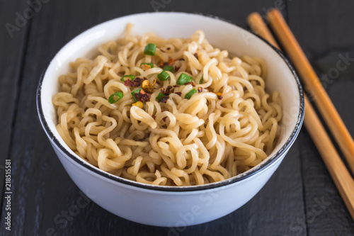 Noodles in bowl on black rustic table with selective focus