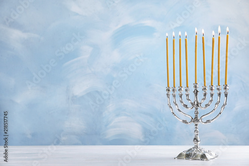 Hanukkah menorah on table against color background
