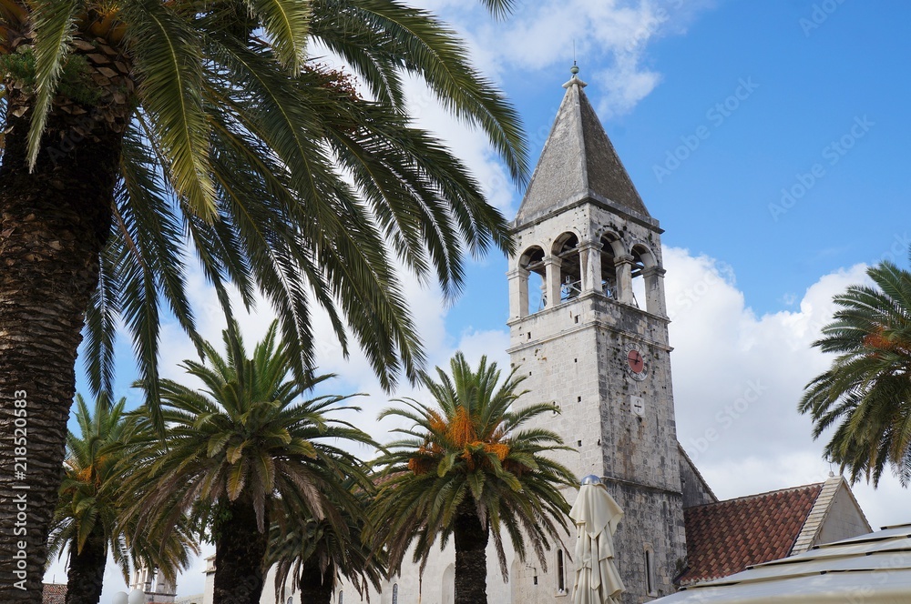 Saint Dominican convent and church in Trogir, Croatia, surrounded by palm trees

