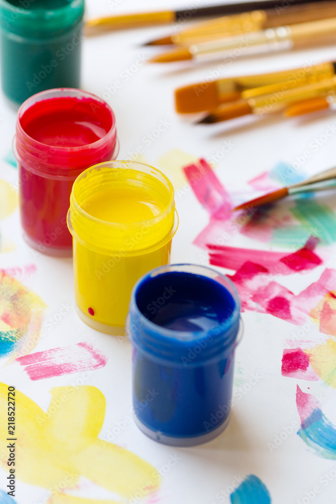 Tempera pain of different colors green blue yellow red brushes on white paper background with colorful strokes. Arts painting creativity education hobbies concept. Lifestyle Tempera pain of different colors green blue yellow red brushes on white paper background with colorful strokes. Arts painting creativity education hobbies concept. Lifestyle