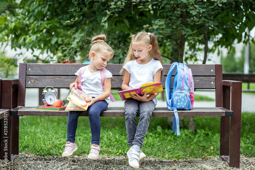 Fototapeta premium Two students read books after classes. The concept of school, study, education, friendship, childhood.