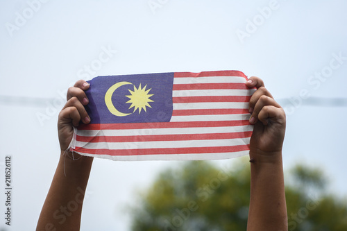 Hand waving Malaysia flag also known as Jalur Gemilang in conjunction with the Independence Day celebration or Merdeka Day.