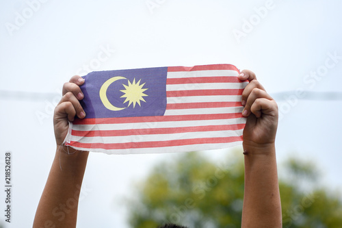 Hand waving Malaysia flag also known as Jalur Gemilang in conjunction with the Independence Day celebration or Merdeka Day. photo