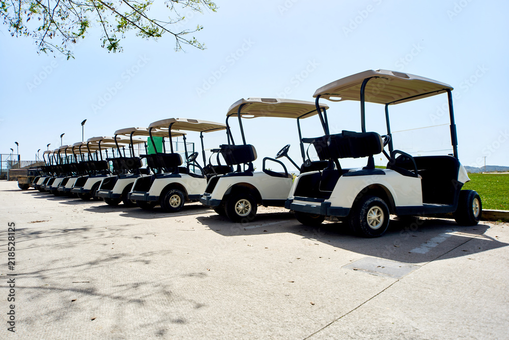 Golf cars or golf carts in a row outdoors 
