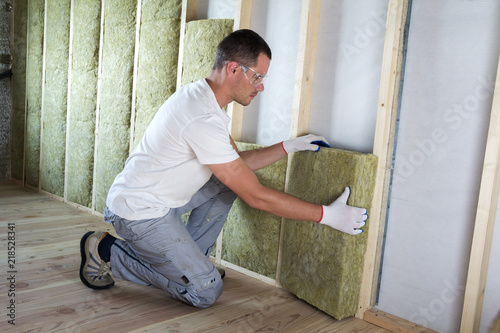 Εκτύπωση καμβά Worker in protective goggles and respirator insulating rock wool insulation in wooden frame for future house walls for cold barrier