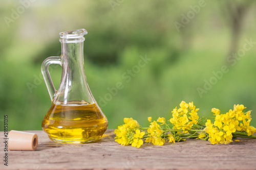 rapeseed oil (canola) and rape flowers on wooden table photo