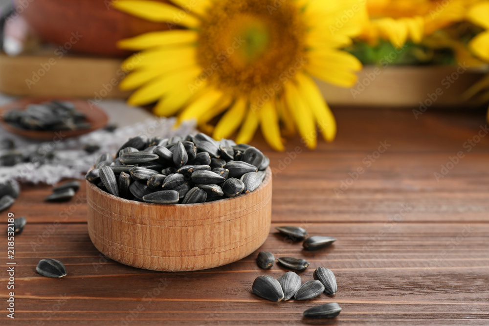 Obraz premium Bowl with sunflower seeds on wooden table, closeup
