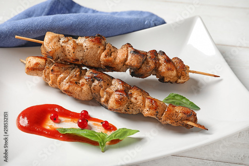 Plate with juicy shish kebab and sauce on table, closeup