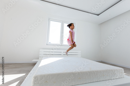 Cute little girl jumping on white bed