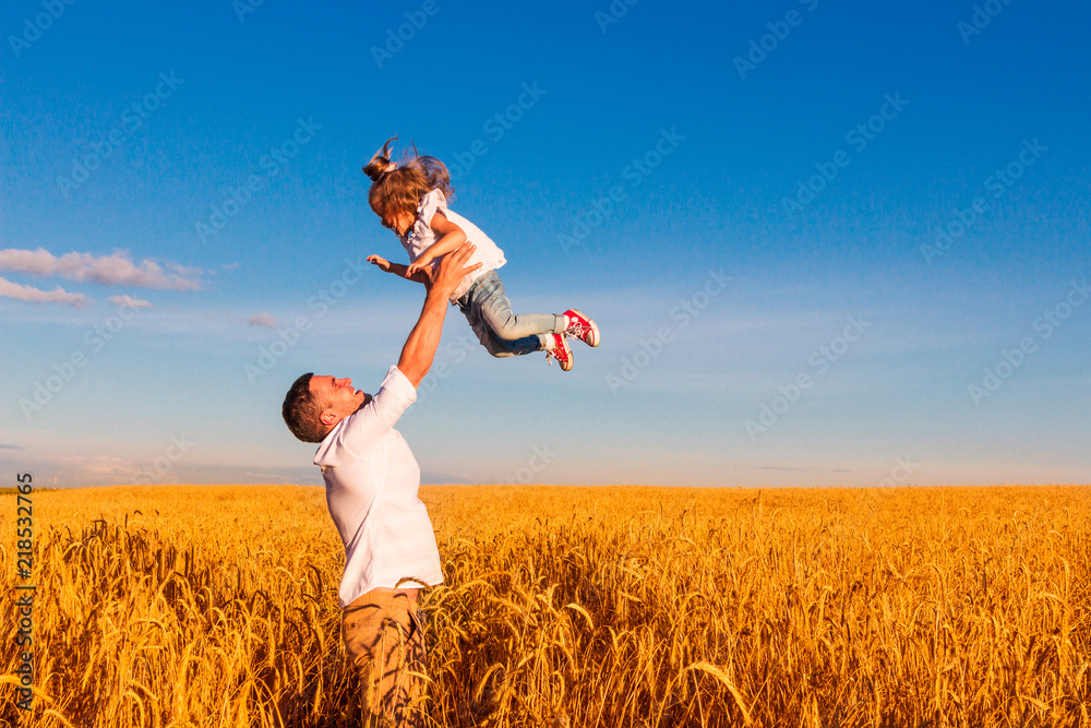 Happy family - the father throws his daughter in the middle of a wheat field on a sunny summer day. Concept of freedom Happy family - the father throws his daughter in the middle of a wheat field on a sunny summer day. Concept of freedom