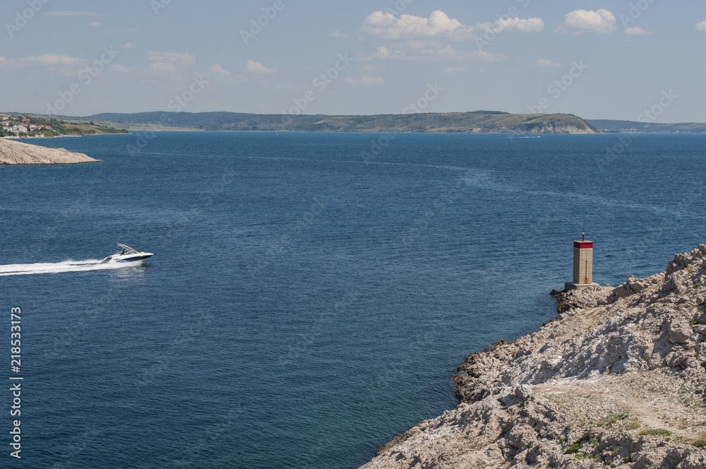 Croazia: il piccolo faro rosso sulla scogliera di fronte al Paški Most, il ponte del 1968 che collega la Croazia con l'isola di Pag