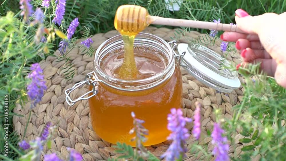 Honey in the jar on the apiary. Hives in the apiary. Spoon for honey.