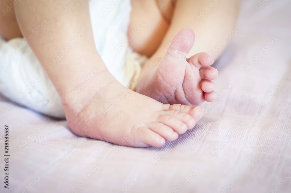 Tiny feet of a newborn baby girl on a gentle pink background. One week year old infant baby. First days of her life image. Tiny feet of a newborn baby girl on a gentle pink background. One week year old infant baby. First days of her life image.