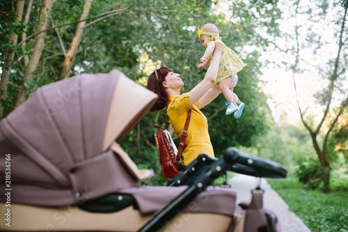 young mother with infant baby and carriage outdoors © sofiko14