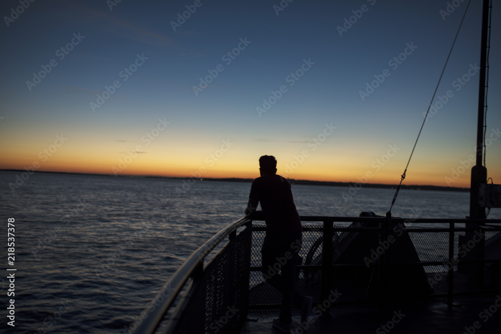Fototapeta premium a guy looks from a boat railling a summer sunset