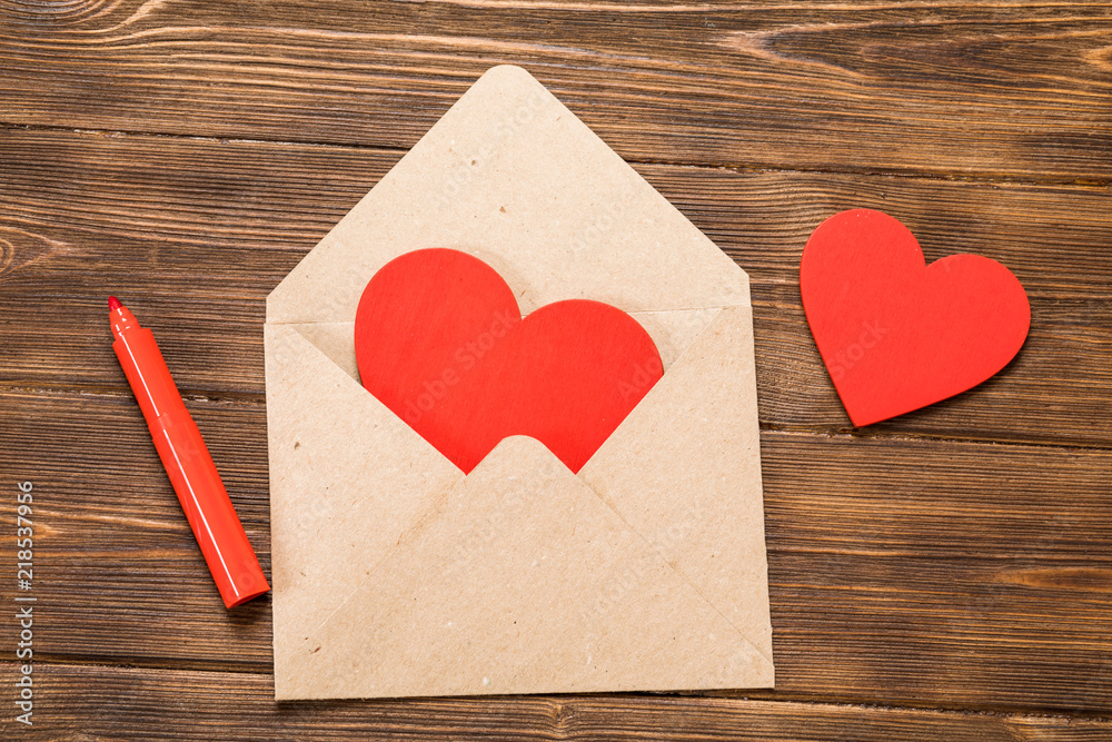 kraft paper envelope with wooden red heart on wooden table with copy space. kraft paper envelope with wooden red heart on wooden table with copy space.
