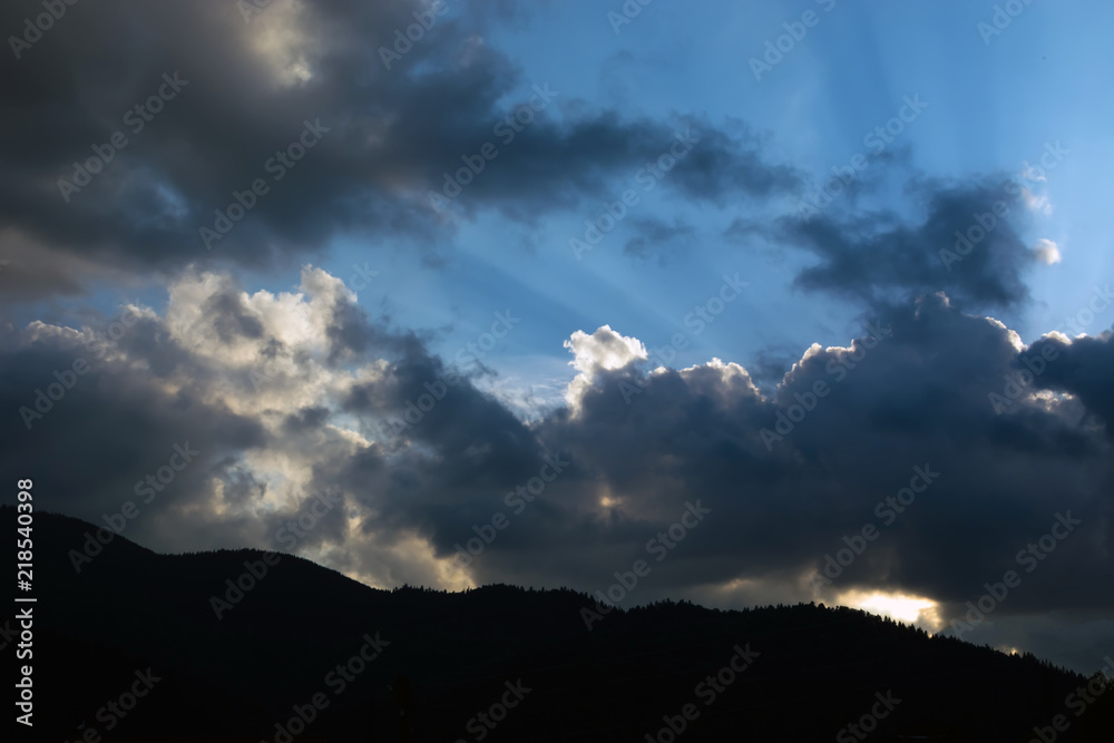 rays of the sun making their way through the clouds against the backdrop of the peaks of the mountains