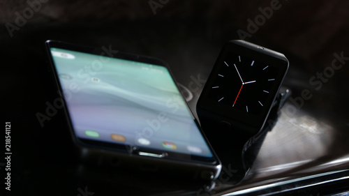 Close up of a smartwatch and a smartphone on a laptop
