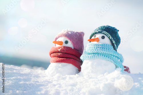 Two little snowmen the girl and the boy in knitted caps and scarfs on snow in the winter. Christmas card with a lovely snowman, copy space © isavira