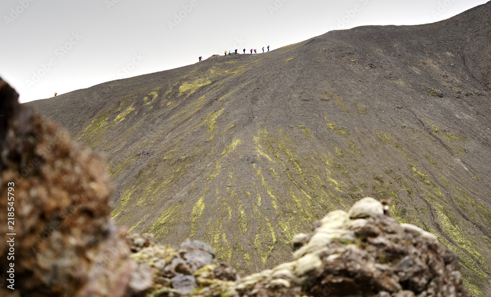 Obraz premium Barren Gray Volcanic Slope with Sparse Green Moss Above a Rocky Foreground in the Rainbow Mountains, Iceland