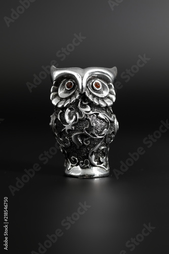 Owl a decorative figure, from different materials, against a dark background.