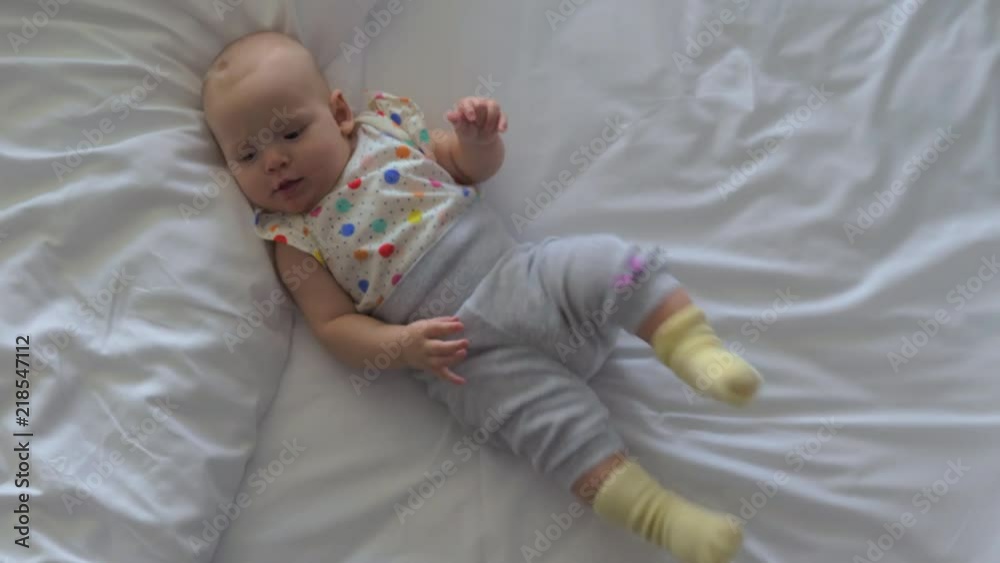 Top view of happy and active baby girl of six months old lying on the bed at home Top view of happy and active baby girl of six months old lying on the bed at home