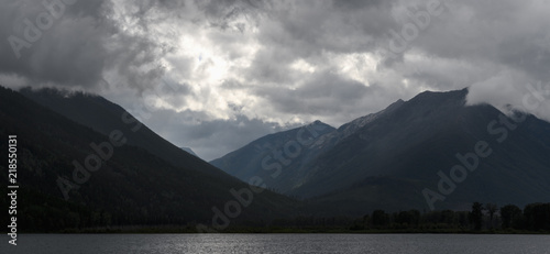 Sun rays peak through dramatic clouds over St Mary Lake in Kimberley, Canada