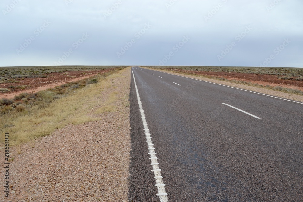 Straight flat road through the desert in outback Australia stretching to the vanishing point