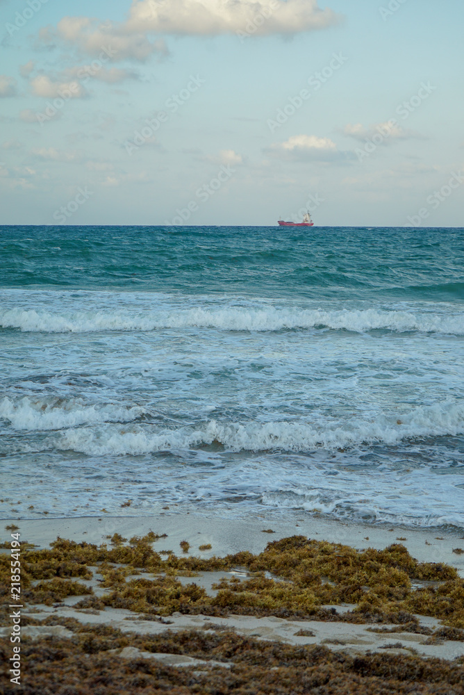 Breezy sunset with colorful ocean waves and ship at Fort Lauderdale Beach in Florida