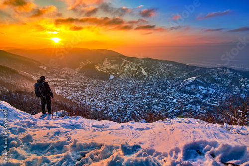 Man admiring the panoramic view of the city Brasov at sunset above the Mount Tampa in the winter time photo