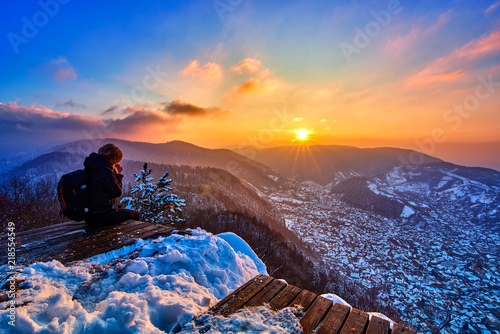 Beautiful woman admiring the panoramic view of the city Brasov at sunset above the Mount Tampa in the winter time photo