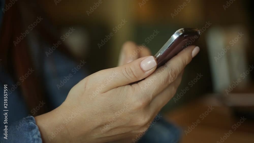 a beautiful Caucasian woman is a middle-aged businessman with red hair and glasses sitting with a smartphone in her hand in a cafe at a table. a beautiful Caucasian woman is a middle-aged businessman with red hair and glasses sitting with a smartphone in her hand in a cafe at a table.