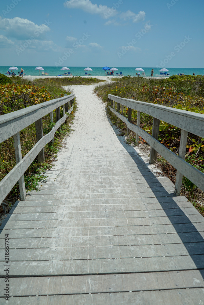 Dramatic vertical view of Wood Bridge looking toward a Sandy Ocean Beach with Colorful Umbrellas on a Sunny Day