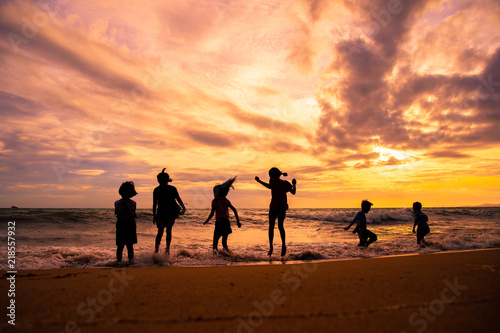 Konstfotografi Silhouette children group enjoy playing sea waves on the beach in sunset with be