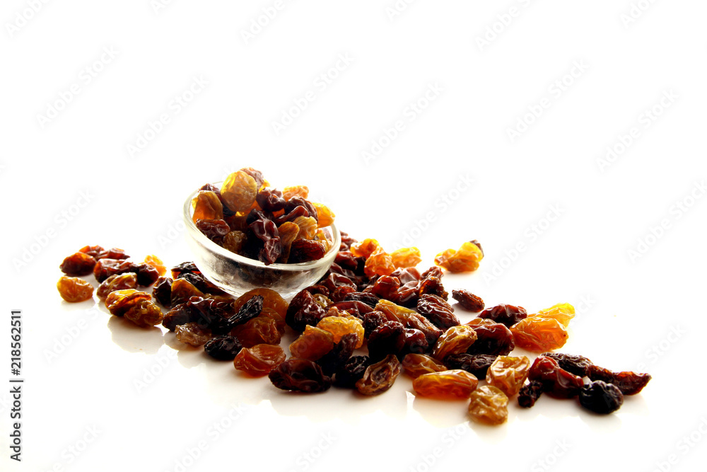 Raisins on white background / A raisin is a dried grape. Raisins are produced in many regions of the world and may be eaten raw or used in cooking, baking, and brewing