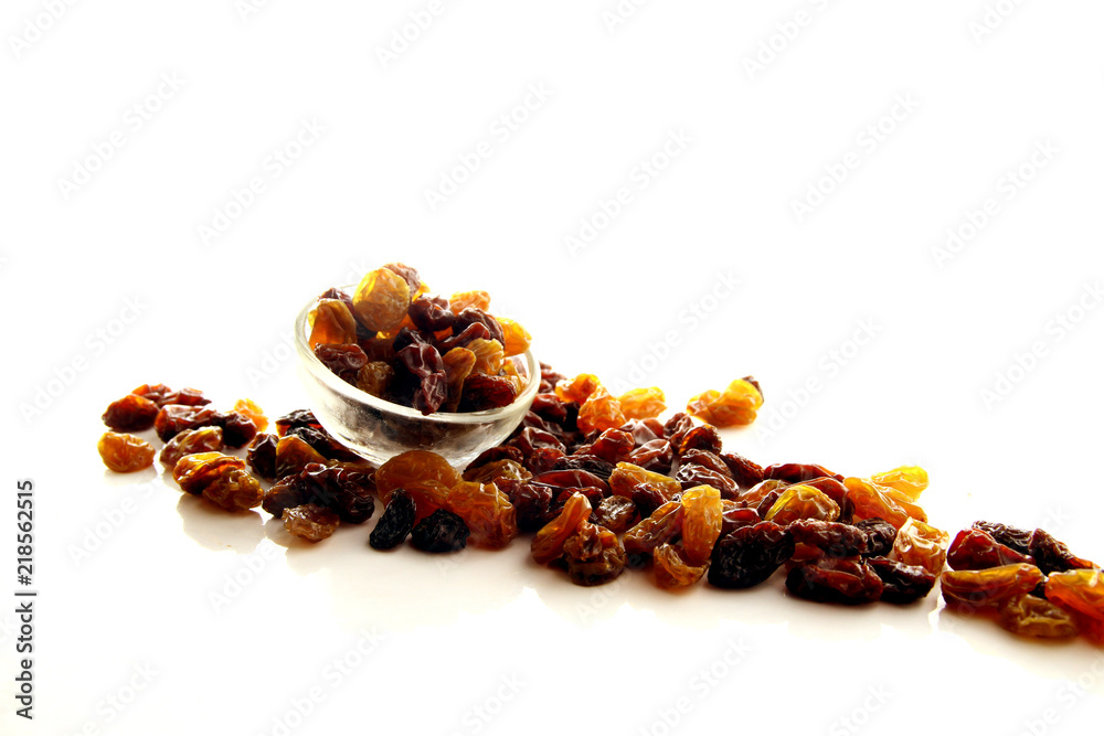 Raisins on white background / A raisin is a dried grape. Raisins are produced in many regions of the world and may be eaten raw or used in cooking, baking, and brewing