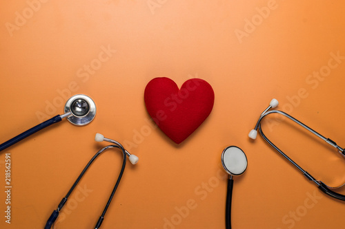 Red heart with stethoscope on orange background. Copy space