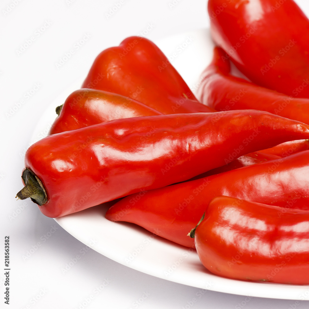 Red peppers closeup in a white plate, white background Red peppers closeup in a white plate, white background