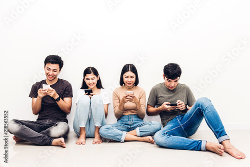 Valokuvatapetti Group of friend sitting relax use technology together of smartphone checking social apps against copy space background
