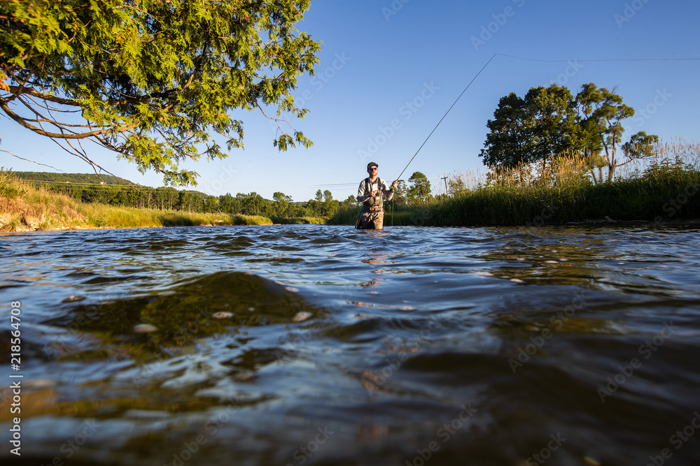 Over underwater shot of a man fly fishing in the summer in a river