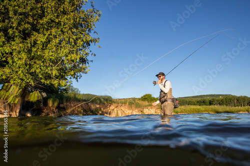 Over underwater shot of a man fly fishing in the summer in a river photo
