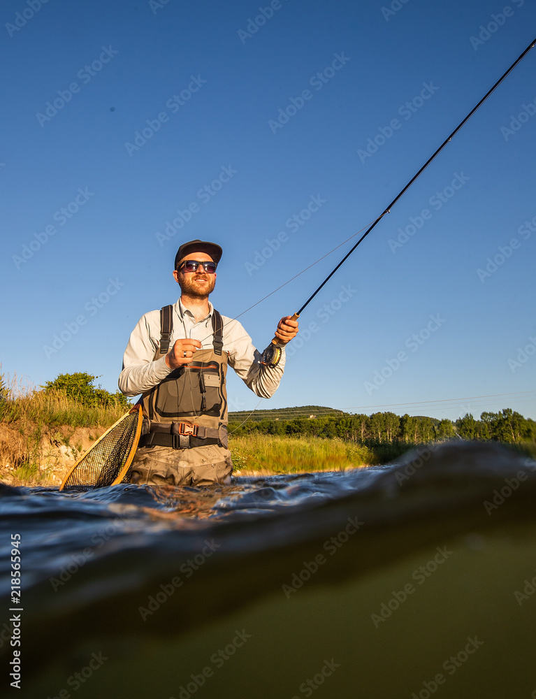 Over underwater shot of a man fly fishing in the summer in a river