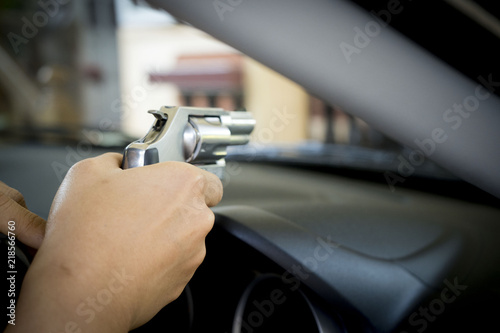 He or she is raising a gun to protect themselves from the villains while down the car.