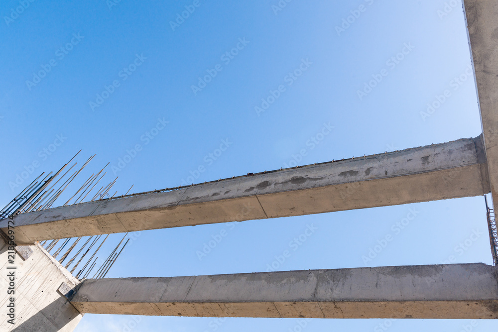 concrete walls and columns in the in the building under construction, in a blue sky background. bottom view