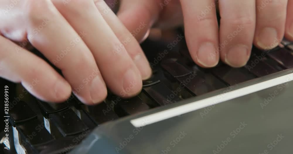 An extreme close shot of a stenographer or court reporter recording information via shorthand using a steno writer or stenograph.